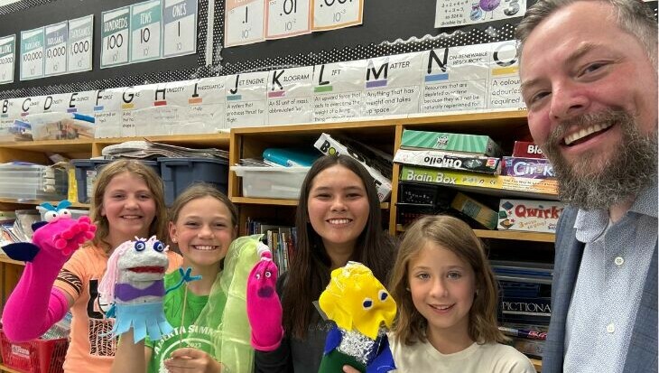 Superintendent Ryan Sawula with four Elnora students who are all holding hand puppets